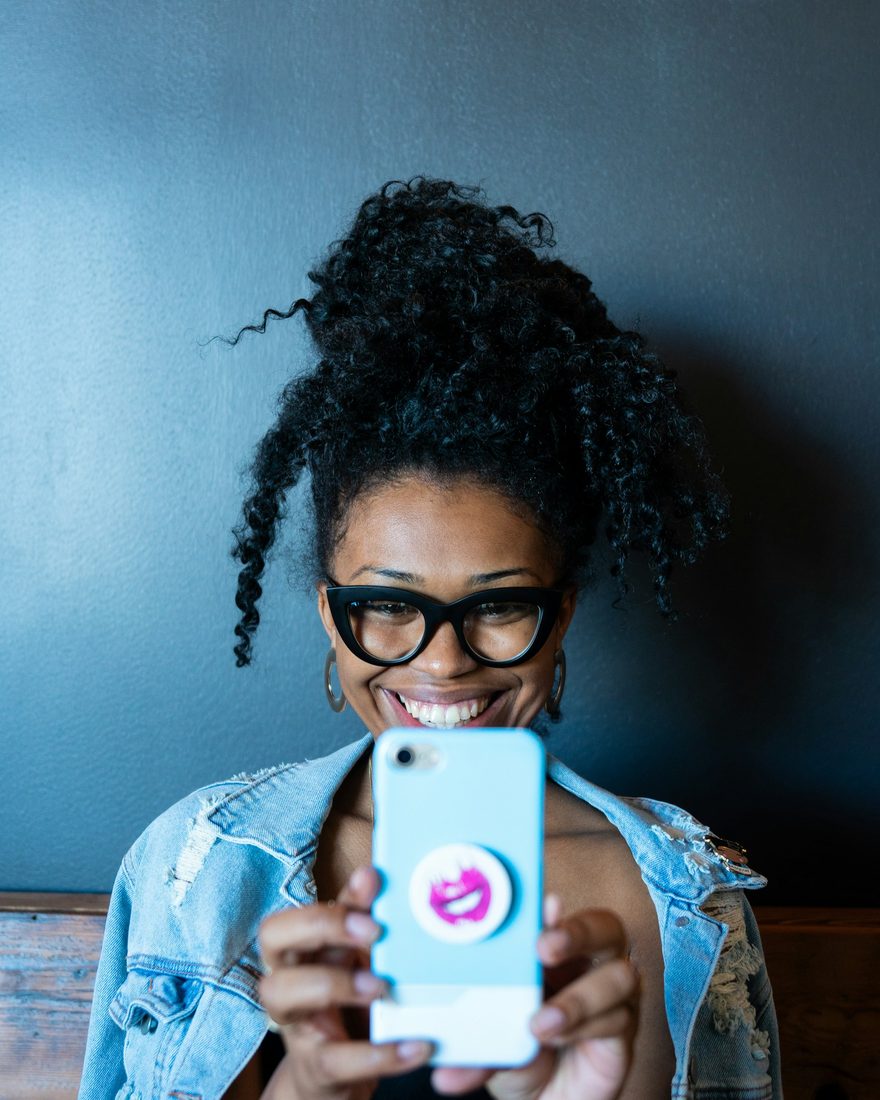 Mulher sorrindo enquanto usa o celular